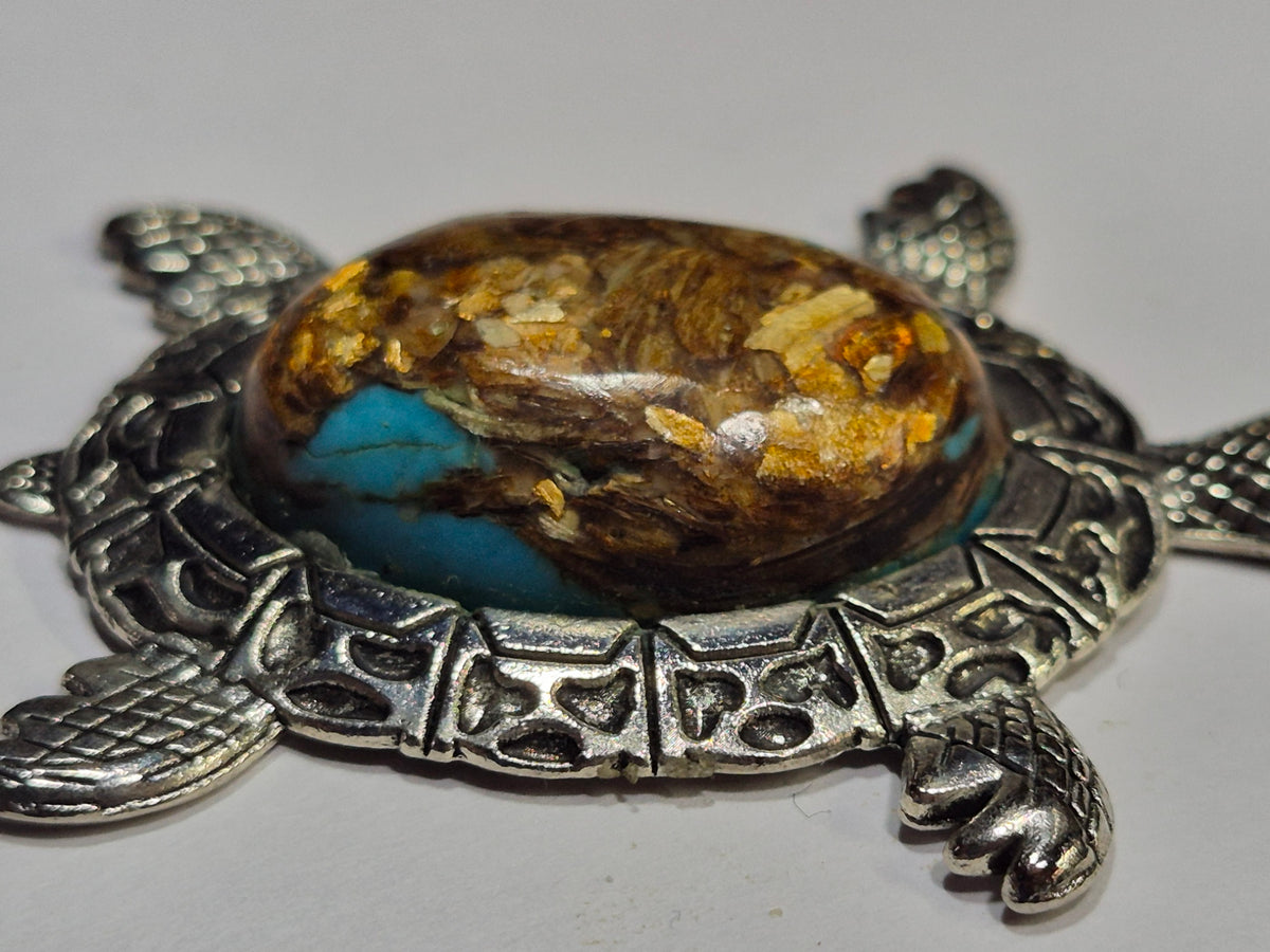 Close-up side view of the turtle's domed brown and turquoise-blue cabochon with golden flecks.