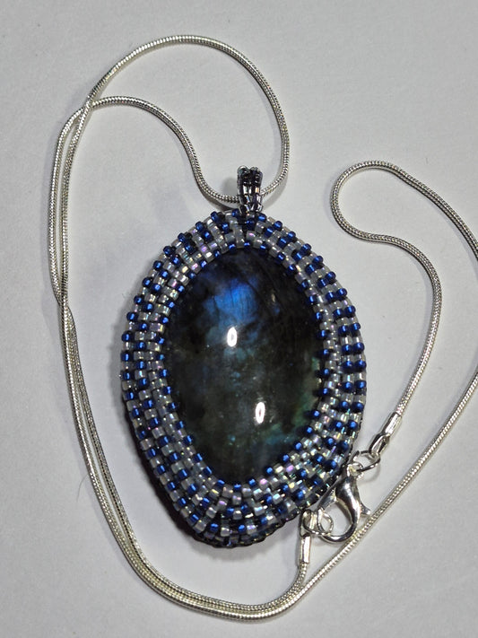 Beadwoven oval cabochon necklace with a silver-tone chain and clasp on a white surface.