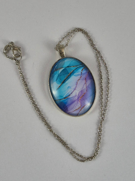 Blue and lavender oval pendant necklace and chain laid out on a pale background.