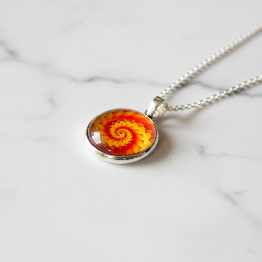 Orange yellow spiral fractal petite pendant necklace angled view on marble surface