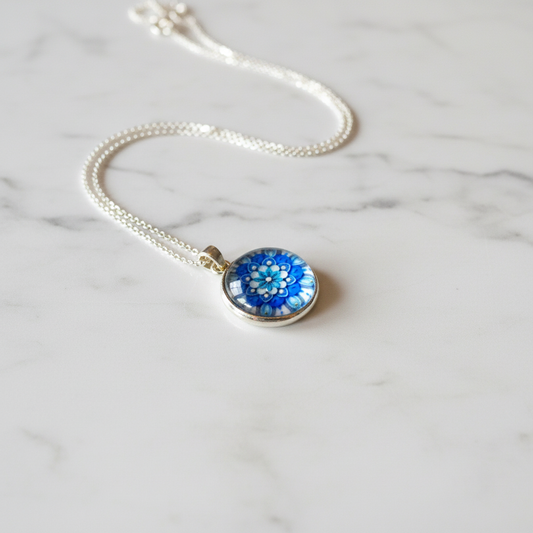 Blue flower mandala petite pendant necklace angled view on marble surface