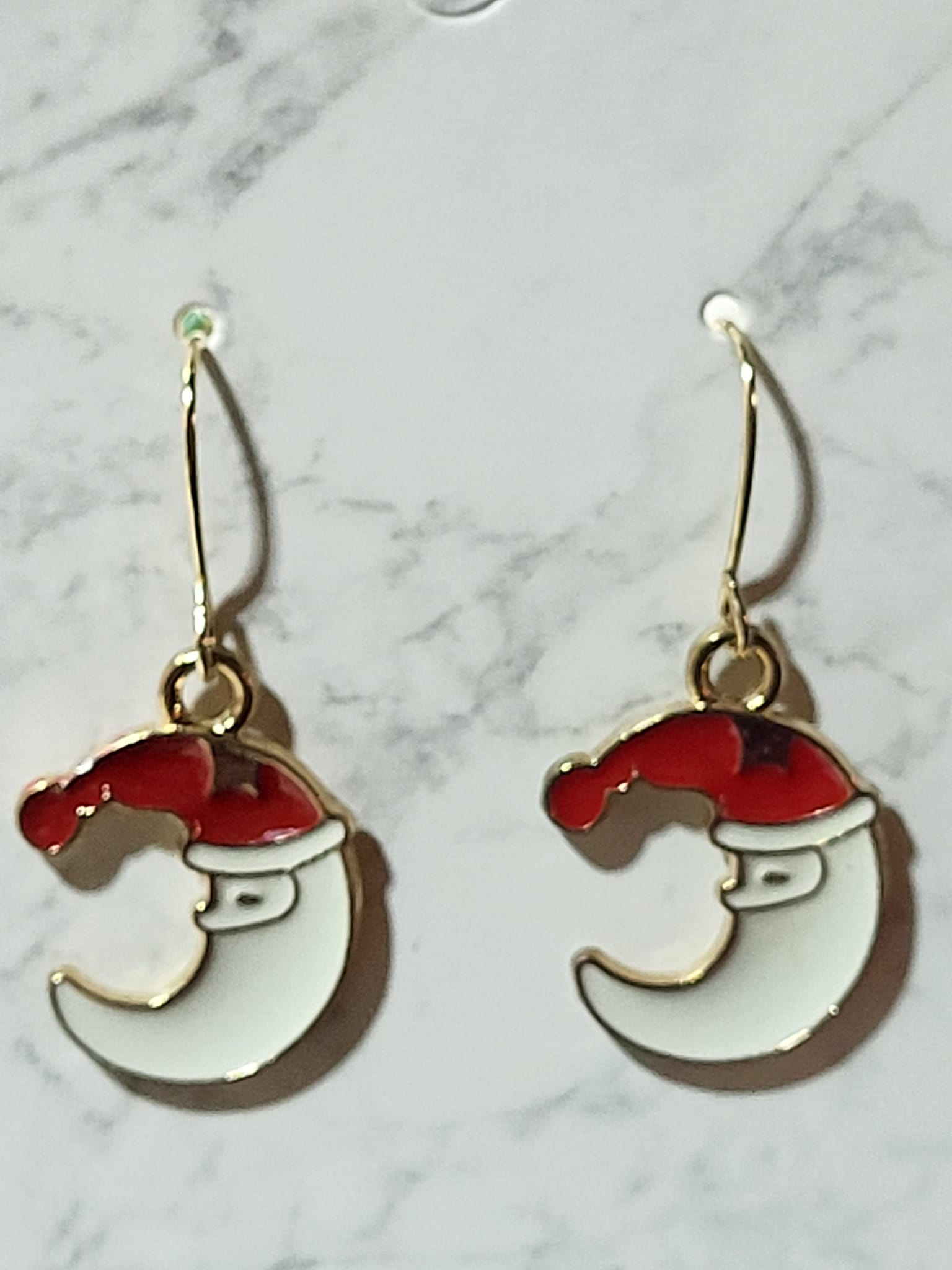 Santa crescent moon face enamel dangle earrings with red hat and white beard curve on gold French wire on marble surface