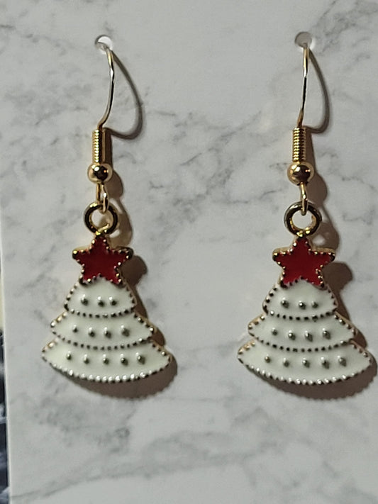White enamel Christmas tree dangle earrings with gold dot tier detail and red enamel star topper on gold French wire on marble surface