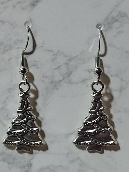 Antique silver Christmas tree charm dangle earrings with star topper and garland detail on silver French wire on marble surface