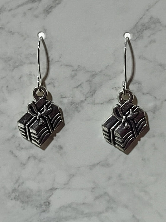 Silver 3D gift box charm dangle earrings with ribbed sides and bow detail on silver French wire on marble surface