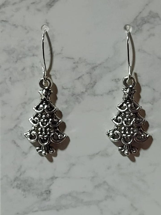 Ornate antique silver filigree Christmas tree charm dangle earrings with tiered scroll detail and star topper on silver French wire on marble surface
