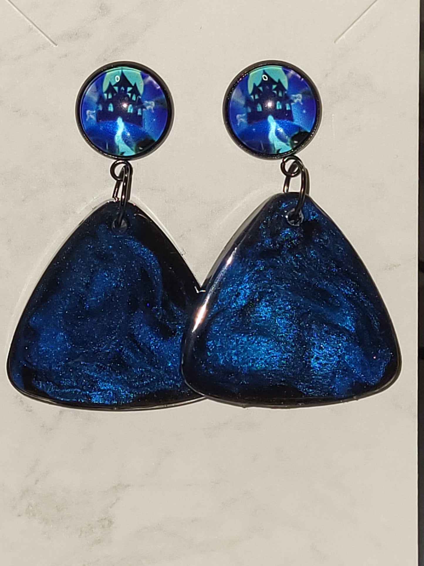 Deep midnight blue shimmer resin triangle dangle earrings with haunted house photo cab studs on marble display card