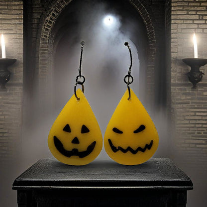 Jack-o-lantern glow in the dark resin teardrop earrings with mismatched pumpkin faces styled in spooky candlelit gothic archway scene
