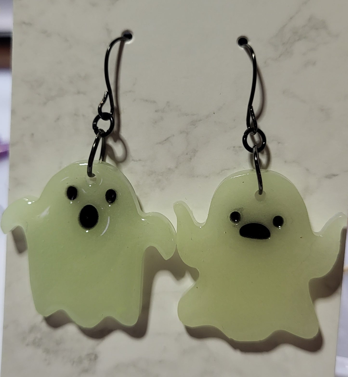Mismatched ghost glow in the dark resin earrings in daylight showing white resin with slight yellow-green tint