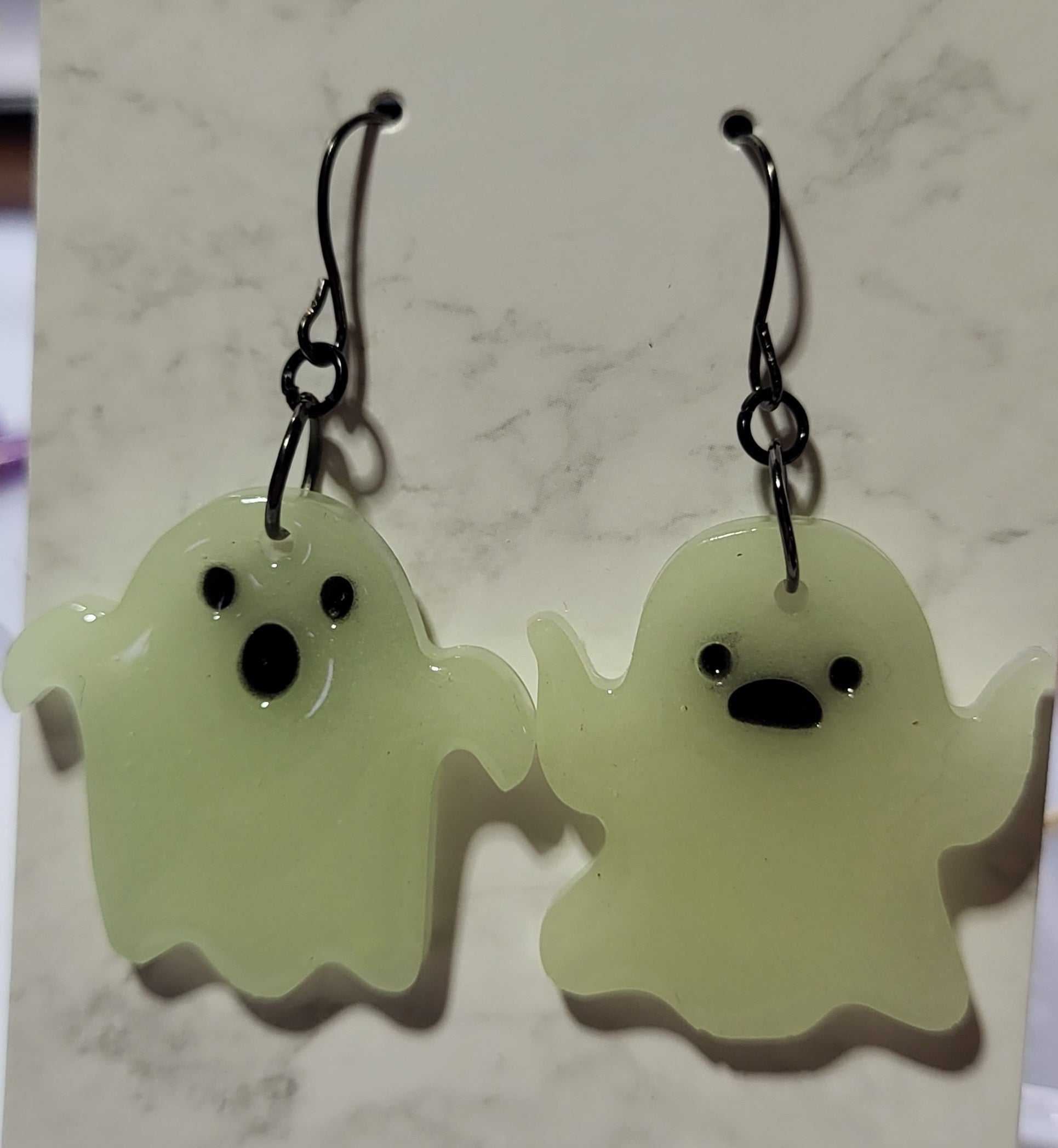 Mismatched ghost glow in the dark resin earrings in daylight showing white resin with slight yellow-green tint