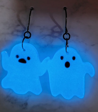Mismatched waving ghost resin earrings glowing vivid electric blue in the dark