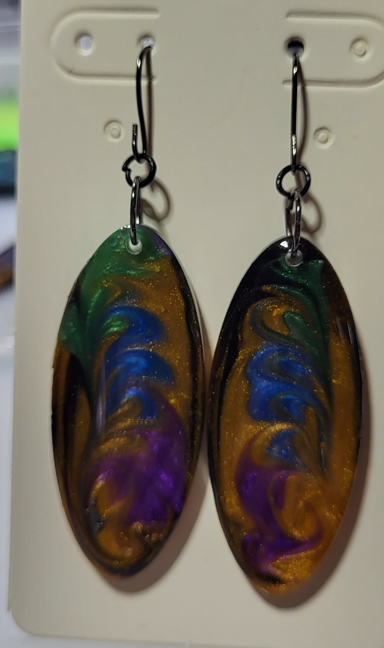 Large oval resin earrings with rich galaxy swirl of purple, blue, gold, and green with gold shimmer on earring card