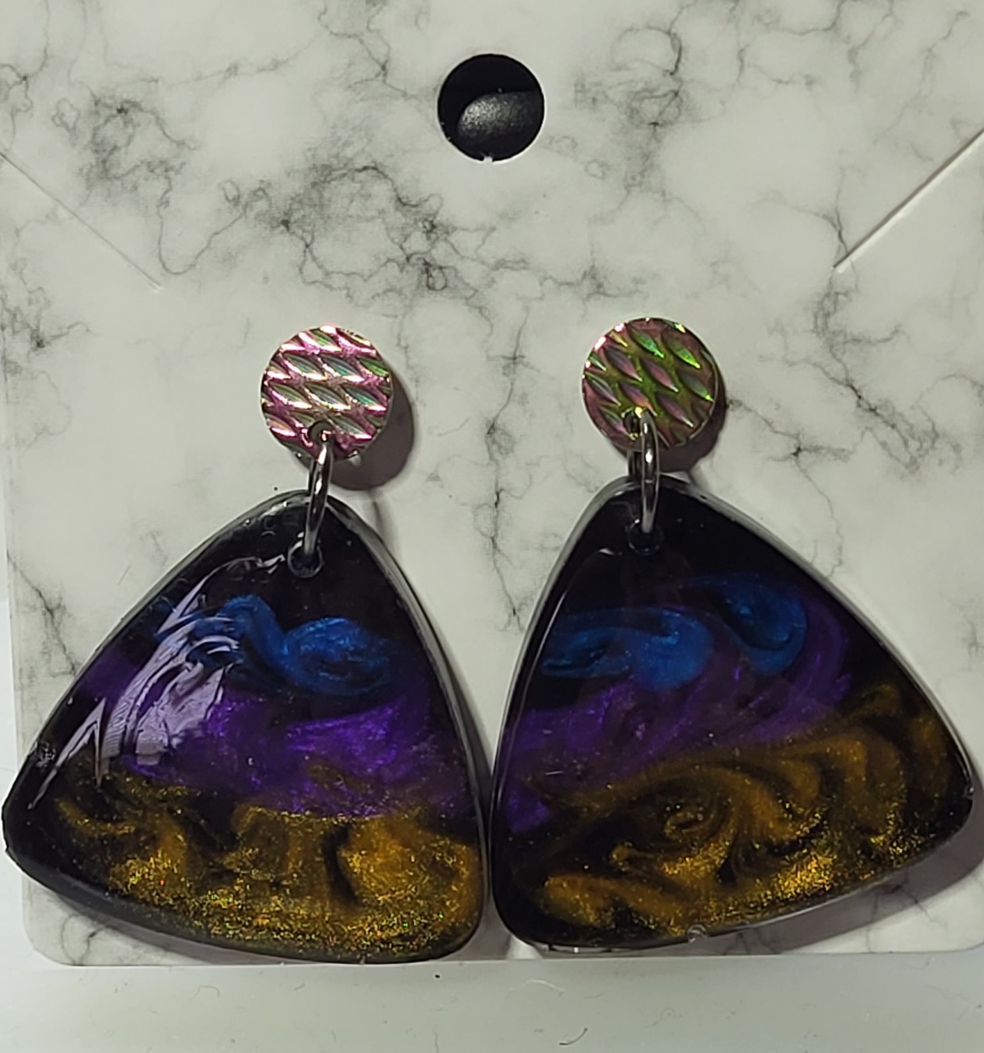 Two-piece drop earrings with iridescent holographic circle stud top and large rounded triangle resin pendant in deep purple, cobalt blue, and gold glitter swirl on black base