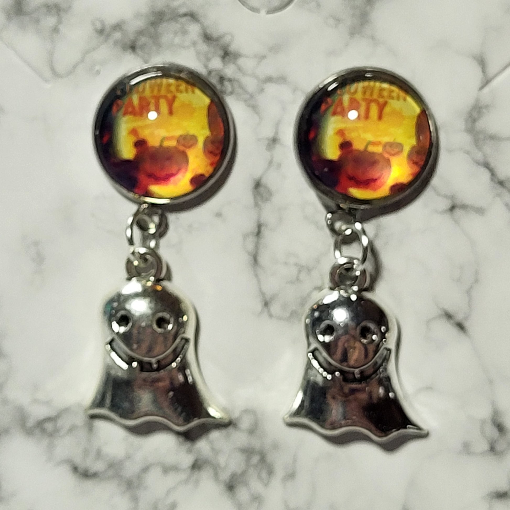 Halloween party glass dome cab stud top with smiling silver ghost charm on marble surface