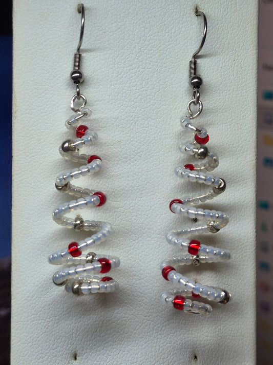 Handmade spiral wire Christmas tree earrings with clear white delica seed beads and red silver bead accents on silver French wire on white earring card