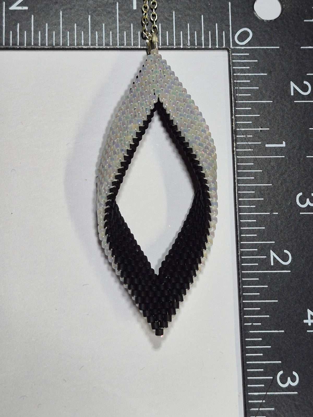 Black and white Miyuki Delica leaf pendant beside rulers showing its size.