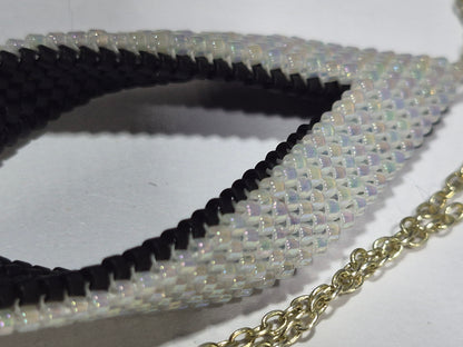 Close-up of shimmering white Delica beads along the open leaf pendant's black inner edge.