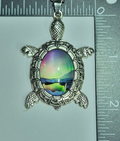 Sea turtle aurora cabochon pendant beside rulers showing its size.