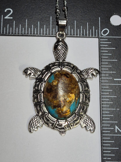 Sea turtle cabochon pendant beside rulers showing its size and detailed silver-tone setting.
