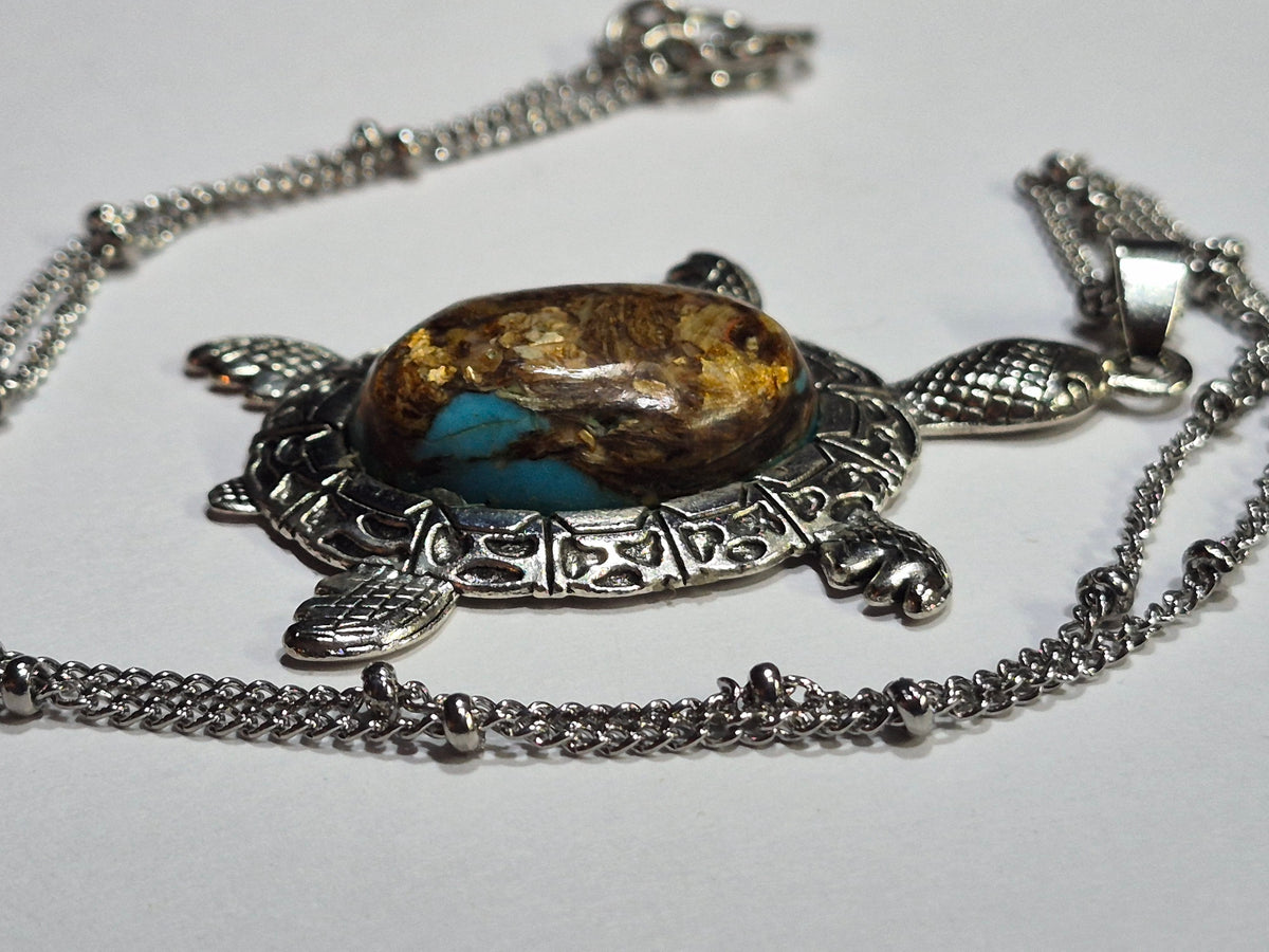 Angled view of the sea turtle necklace showing the raised cabochon and textured flippers.