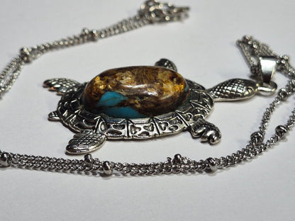 Angled view of the sea turtle necklace showing the raised cabochon and textured flippers.