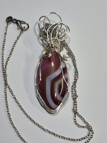 Purple banded pendant necklace with silver-tone copper wirework and chain on a white background.
