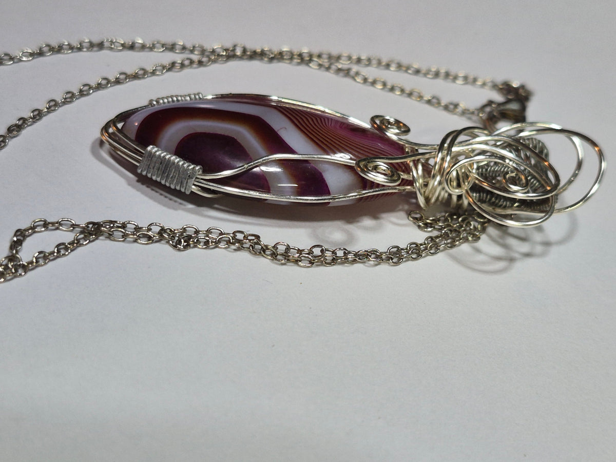 Side view of the banded oval pendant showing its curved surface and silver-tone wire setting.