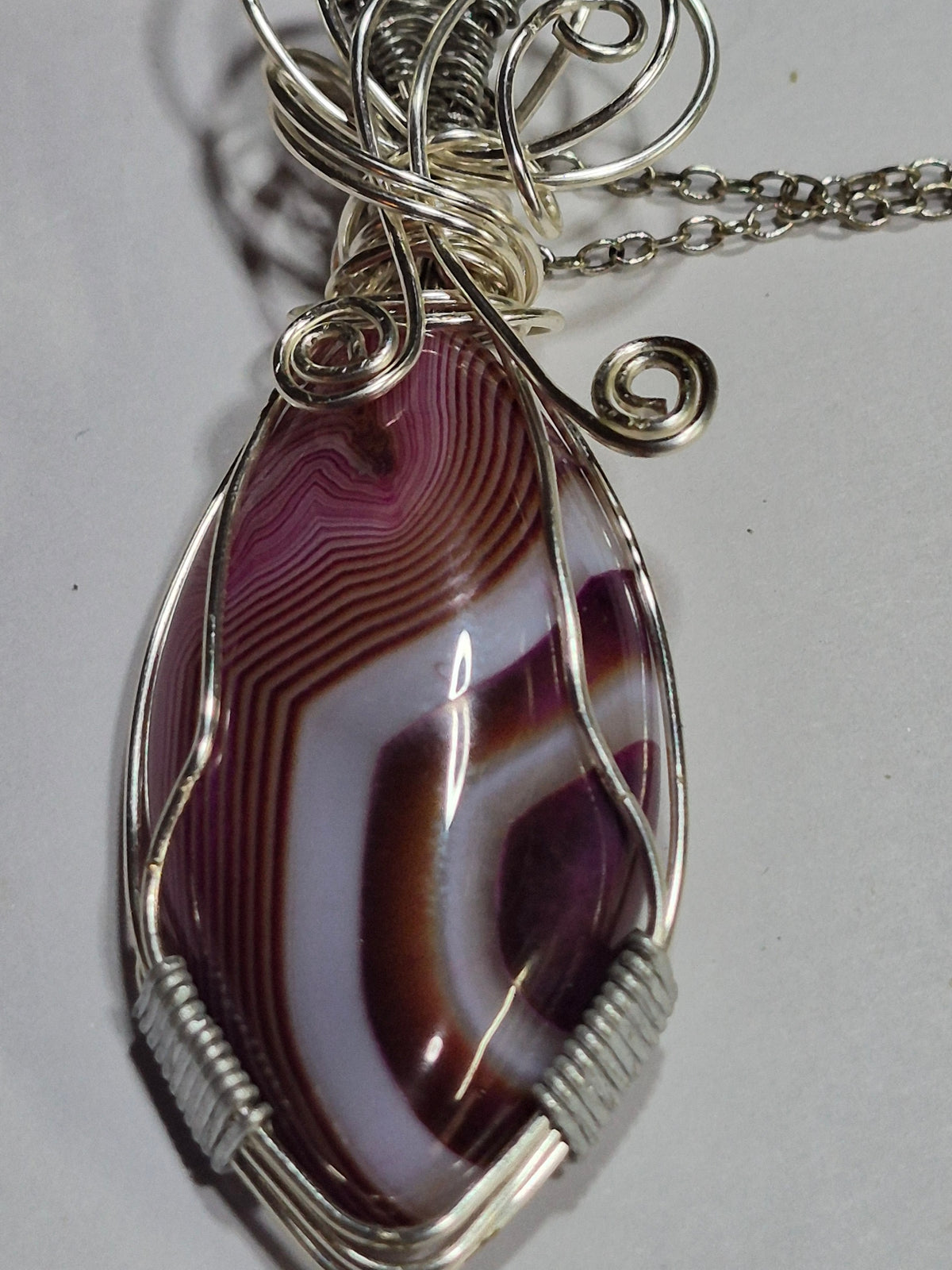 Close-up of purple, brown, and white banding framed by silver-tone wire coils and spirals.