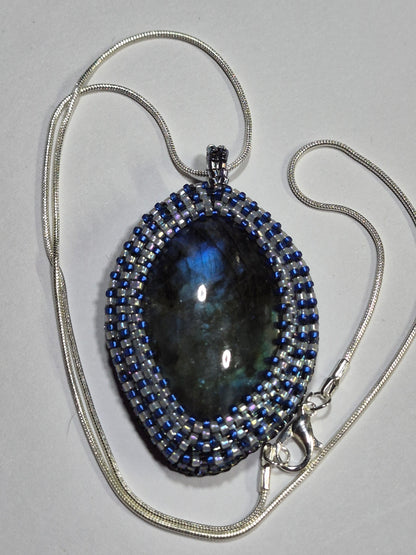 Beadwoven oval cabochon necklace with a silver-tone chain and clasp on a white surface.