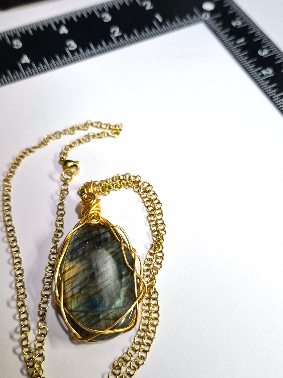 Labradorite necklace laid out on white with a ruler above it.