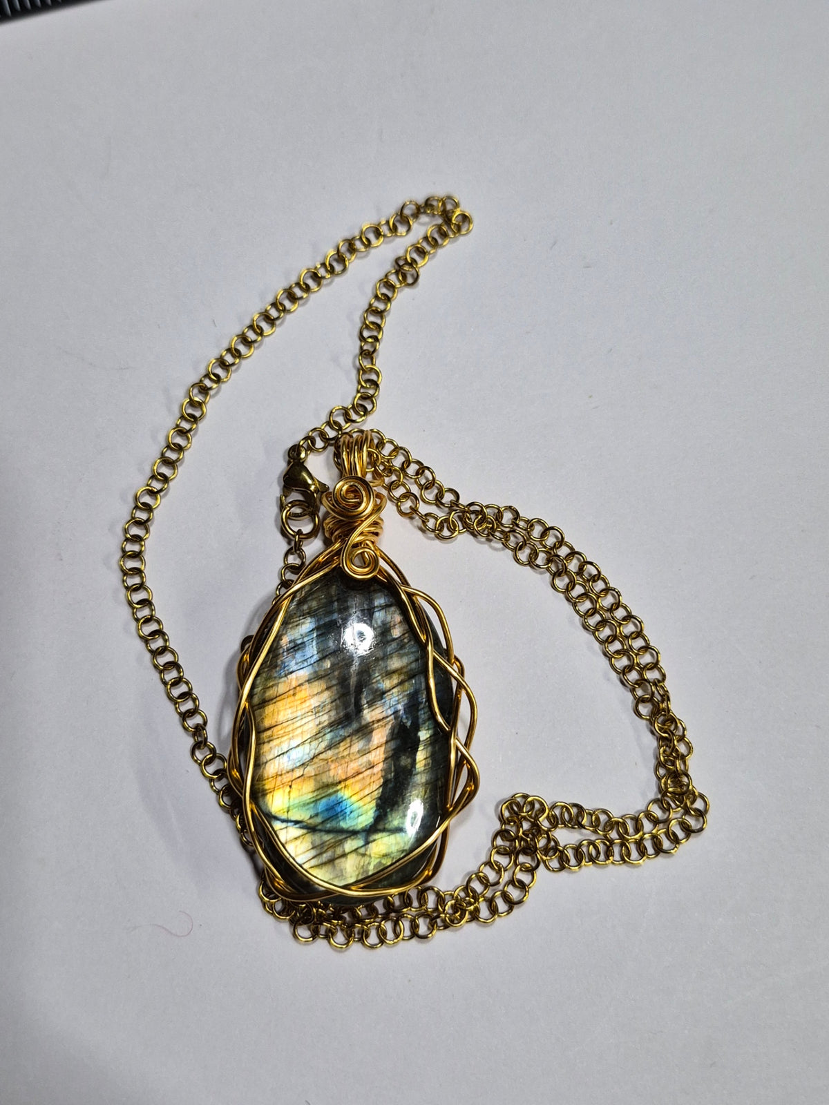 Labradorite pendant displaying gold, green, and blue flashes with its gold-tone chain.
