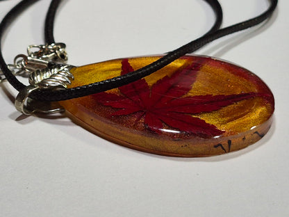 Side view of the maple leaf resin pendant showing its thickness and glossy surface.