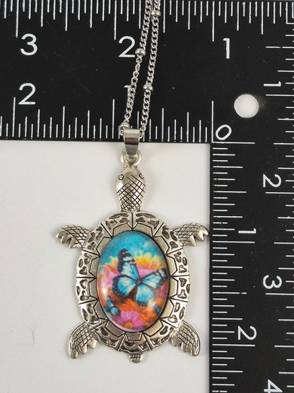 Butterfly floral sea turtle pendant beside a ruler for scale.