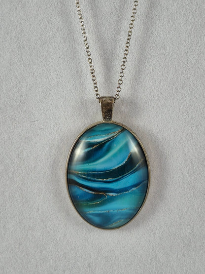 Ocean blue swirl oval cabochon pendant in a silver-tone frame hanging on a chain.