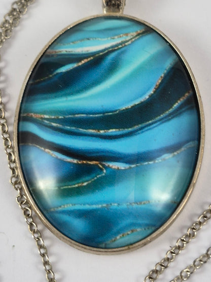 Close-up of layered blue swirls and fine gold-toned lines on the oval cabochon.