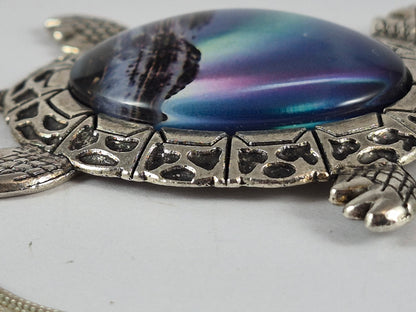 Side view showing the domed aurora cabochon and detailed silver-tone turtle frame.
