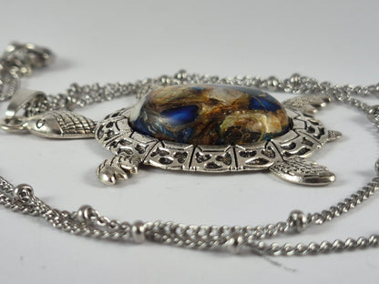 Side view showing the domed mosaic-style cabochon and textured silver-tone sea turtle frame.