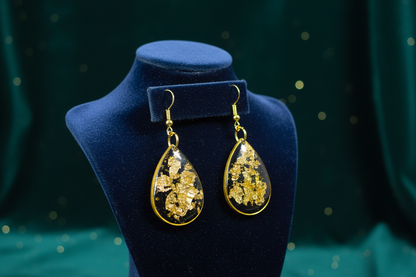 Black and gold earrings on rich velvet display