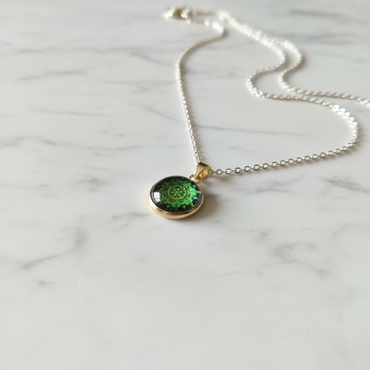 Green spiral mandala petite pendant necklace angled view on marble surface