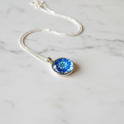 Blue flower mandala petite pendant necklace angled view on marble surface