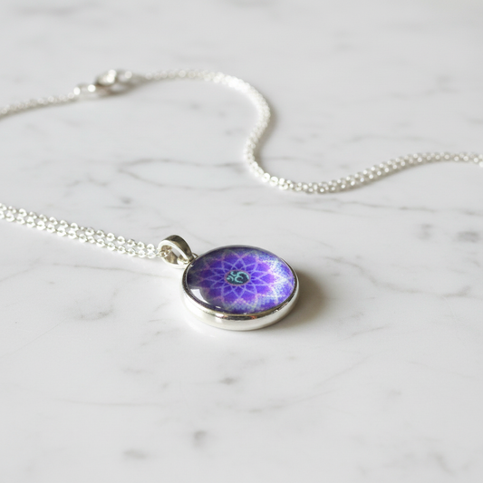 Purple Om mandala petite pendant necklace angled view on marble surface