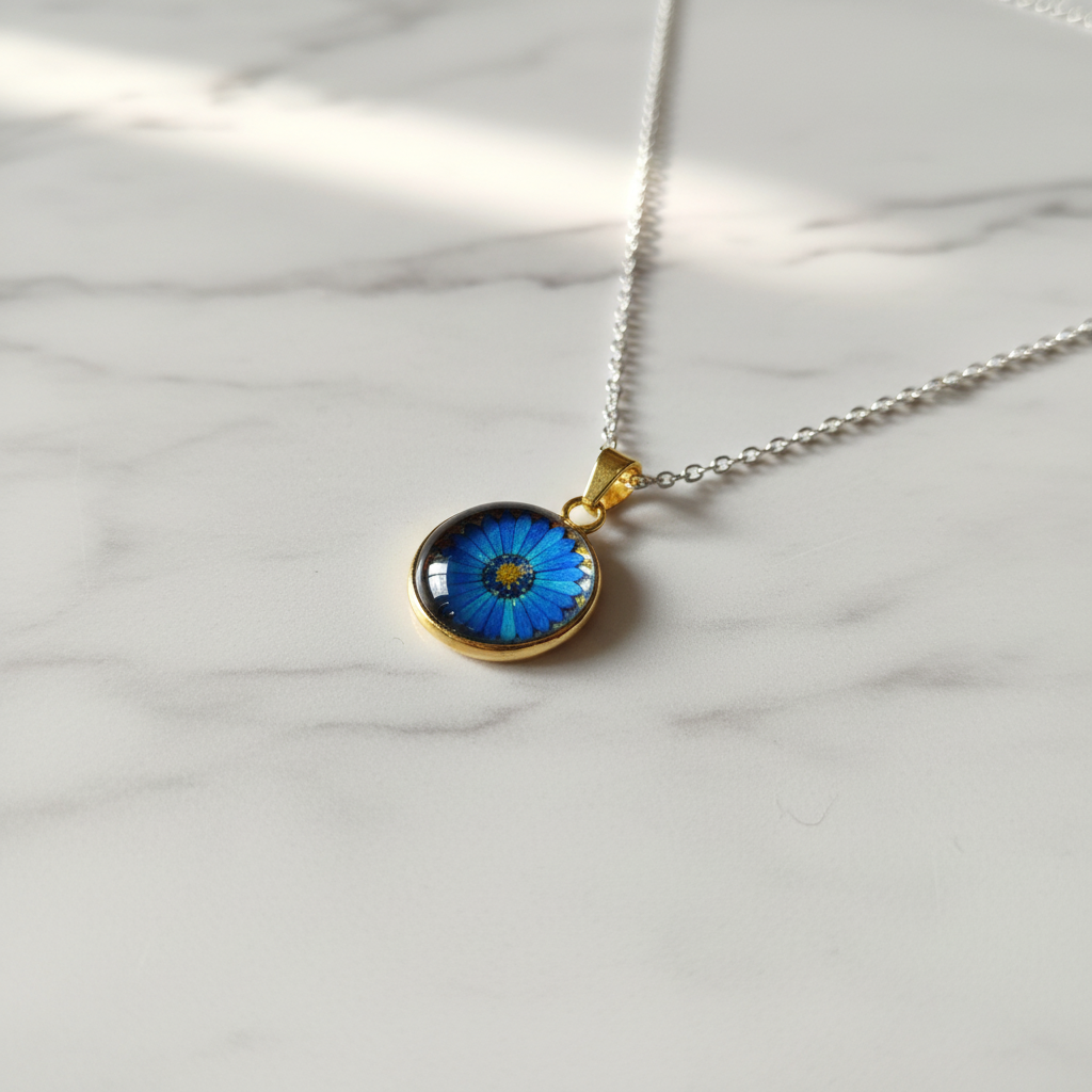 Blue daisy flower petite pendant necklace angled view on marble surface