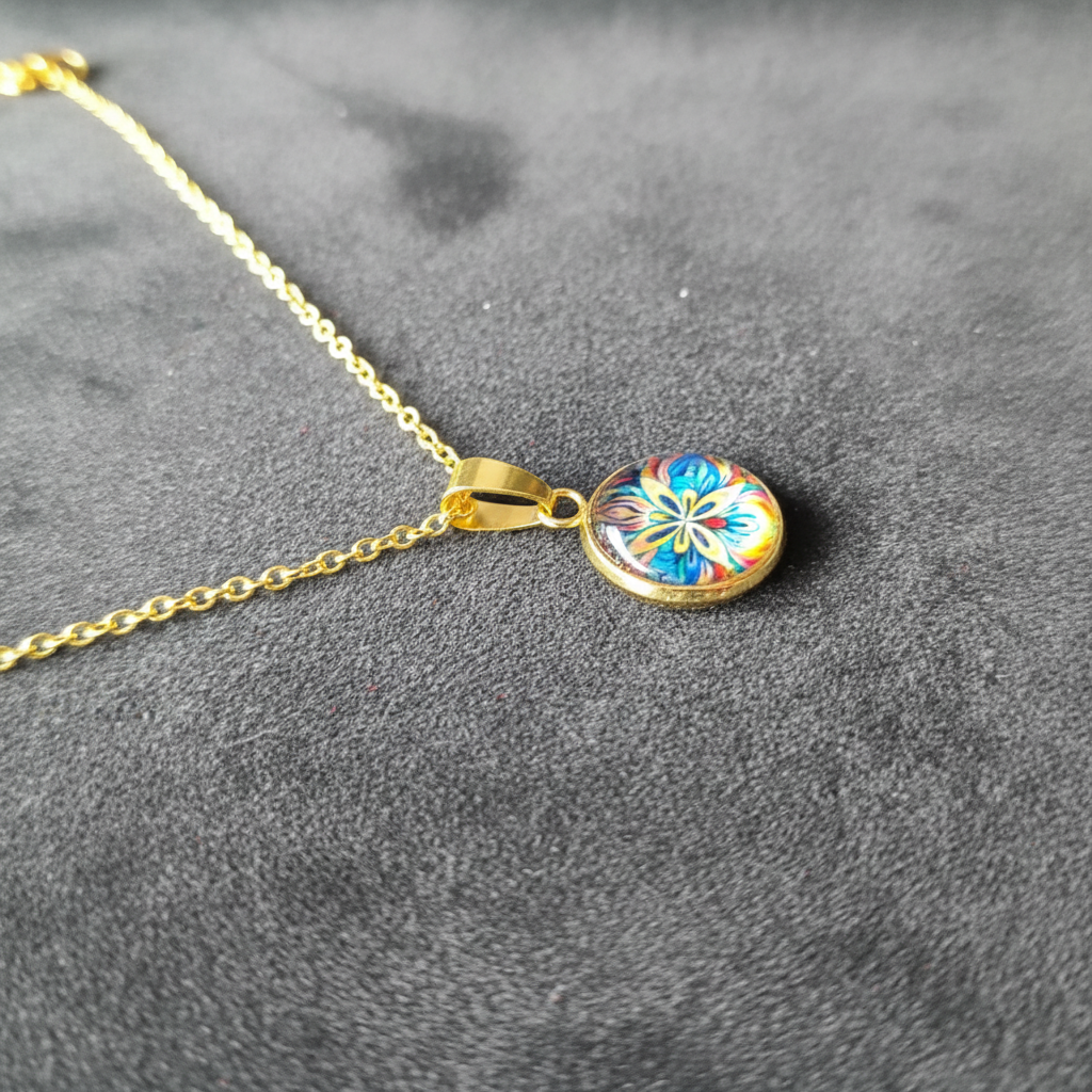 Angled view of petite vibrant pansy flower pendant on velvet background