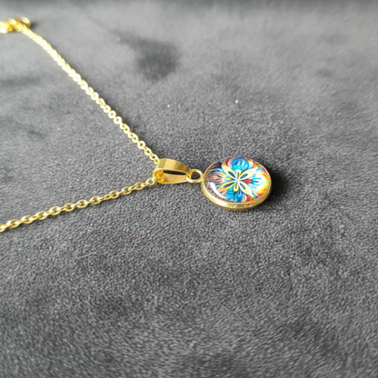 Angled view of petite vibrant pansy flower pendant on velvet background