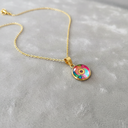 Angled view of petite abstract watercolor sunflower pendant on velvet background