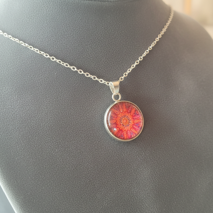 Angled view of petite red coral mandala pendant on velvet background