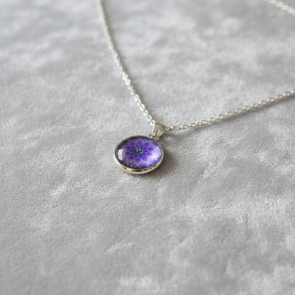 Angled view of petite purple Om mandala pendant on velvet background