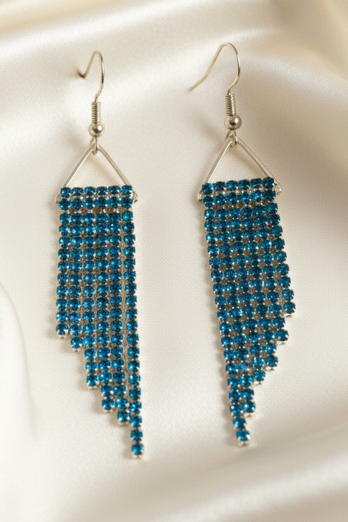 Teal crystal cup chain fringe earrings on ivory satin, front view
