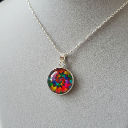 Angled view of petite rainbow kaleidoscope mandala pendant on velvet background