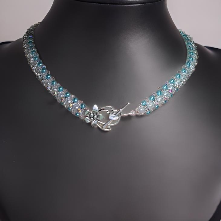 Teal and white beadwoven collar necklace on mannequin bust showing silver floral toggle clasp